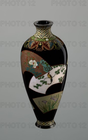 Vase by Namikawa Yasuyuki 1845–1927, ca. 1890–1905 Meiji period. A small, slender cloisonné enamel vase, height 18.0 cm, diameter 7.8 cm. The body tapers toward the bottom and terminates in a ring-shaped silver foot; the short neck is slightly parted at the spout and enclosed by a silver ring. An ornamental shippo motif border with rosettes in rhomboid fields encircles the foot and a similar border adorns the neck. From the neck a decoration of petals filled with stylized phoenix images flows down to the shoulders. The belly is covered with shiny black enamel and decorated with six colorful fan-shaped reserves showing various floral and bird motifs, executed with meticulous precision in the yusen technique using silver wires. A silver plaque mounted in the mirror of the bottom is engraved “Kyoto Namikawa.” Made in Kyoto, Japan., A tall, glossy vase with a narrow neck and flared rim sits against a neutral gray background; the vase has a predominantly black surface interrupted by several...