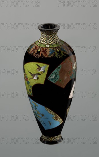Vase by Namikawa Yasuyuki 1845–1927, ca. 1890–1905 Meiji period, 1868–1912, Kyoto, Japan. Small slender cloisonné enamel vase, height 18.0 cm, diameter 7.8 cm. Body tapers to a ring-shaped silver foot; short neck slightly parted at the spout enclosed by a silver ring. Ornamental shippo border with rosettes in rhomboid fields at the foot and neck. Petal motifs filled with stylized phoenixes flow down to the shoulders. Belly covered with shiny black enamel decorated with six colorful fan-shaped reserves showing various floral and bird motifs, executed in the yusen technique with silver wires. Silver plaque mounted in the mirror of the base engraved: Kyoto Namikawa., A tall, glossy vase with a rounded body tapering to a narrow foot and neck, primarily black with decorative panels and bands in colors including green, blue, brown, gold, white, red, and turquoise; the neck and foot have a patterned band in cream and gold with dark accents, a floral ring in green and gold sits below the neck,...