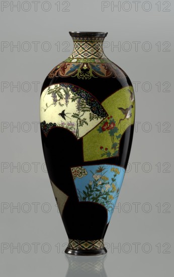 Vase, Namikawa Yasuyuki 1845–1927, enameller. Meiji period, ca. 1890–1905. Kyoto, Japan. Cloisonné enamel vase, height 18.0 cm, diameter 7.8 cm. A small, slender vase with a body tapering toward the bottom and terminating in a ring-shaped silver foot. The arms merge into a short neck slightly parted at the spout, enclosed by a silver ring. At the foot is an ornamental shippo cloisonné border with rosettes inscribed in rhomboid fields; a similar ornament adorns the neck. From the neck a decoration of petals filled with stylized images of a phoenix flows down to the shoulders. The belly is covered with shiny black enamel decorated with six colorful reserves in the shape of unfolded fans, each bearing floral and bird motifs executed with meticulous precision in the yusen technique using silver wires. On the foot, in the mirror of the bottom, a silver plaque with an engraved signature is mounted: Kyoto Namikawa., An elongated vase with a glossy black background featuring a patchwork of dec...