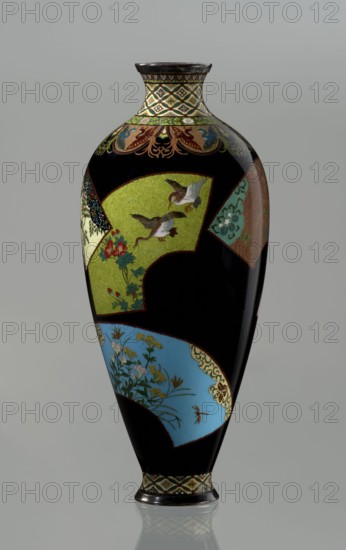 Vase by Namikawa Yasuyuki 1845–1927, cloisonné enamel, ca. 1890–1905 Meiji period. Small, slender vase with a body tapering toward the bottom and terminating in a ring-shaped silver foot. The arms merge into a short neck slightly parted at the spout, enclosed by a silver ring. At the foot is an ornamental shippo cloisonné border with rosettes in rhomboid fields; a similar ornament adorns the neck, from which a decoration of petals filled with stylized phoenix images flows down to the shoulders. The belly is covered with shiny black enamel decorated with six colorful reserves in the shape of unfolded fans, depicting various floral and bird motifs rendered with meticulous precision in the yusen technique with silver wires. A silver plaque with an engraved signature mounted in the mirror of the bottom reads “Kyoto Namikawa.” Kyoto, Japan. Height 18.0 cm; diameter 7.8 cm., A tall vase with a glossy black background decorated with a few fan-shaped panels in green, blue, turquoise, cream, br...