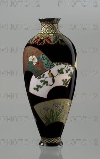 Vase by Namikawa Yasuyuki 1845–1927, ca. 1890–1905 Meiji period. A small, slender cloisonné enamel vase, height 18.0 cm, diameter 7.8 cm. The body tapers toward the bottom and terminates in a ring-shaped silver foot; the short neck is slightly parted at the spout and enclosed by a silver ring. An ornamental shippo motif border with rosettes in rhomboid fields decorates the foot and a similar band the neck. Petal-shaped decorations filled with stylized phoenix images flow down to the shoulders. The belly is covered with shiny black enamel decorated with six colorful fan-shaped reserves bearing various floral and bird motifs, executed with meticulous precision in the yusen technique using silver wires. A silver plaque mounted in the mirror of the bottom is engraved “Kyoto Namikawa.” Japanese; Kyoto., A tall, slender vase with a glossy black background decorated with several fan-shaped panels showing floral and bird motifs; one panel features white and green flowers with red accents on a ...