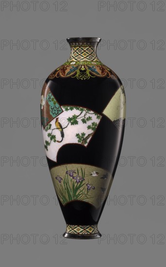 Vase by Namikawa Yasuyuki 1845–1927, enameller. Meiji period ca. 1890–1905, Kyoto, Japan. Small, slender cloisonné vase, height 18.0 cm, diameter 7.8 cm. Body tapers to a ring-shaped silver foot; short neck slightly parted at the spout enclosed by a silver ring. Ornamental shippo cloisonné border with rosettes in rhomboid fields at the foot and neck. Petal decoration with stylized phoenix motifs flowing to the shoulders. Belly covered with shiny black enamel with six colorful fan-shaped reserves showing various floral and bird motifs, executed in the yusen technique with silver wires. Silver plaque mounted in the mirror of the bottom engraved: Kyoto Namikawa., A tall, narrow vase with a glossy black background features decorative panels in shades of white, green, teal, brown, gold, and purple; the neck and base have geometric and floral border patterns in yellow, green, brown, and blue, while a band near the top shows stylized ornate motifs in green, blue, brown, and gold; one fan-shap...