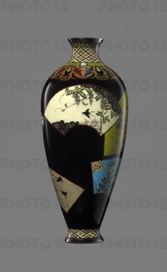 Vase by Namikawa Yasuyuki 1845–1927, ca. 1890–1905 Meiji period, 1868–1912, Kyoto, Japan. Small slender cloisonné enamel vase, height 18.0 cm, diameter 7.8 cm. Body tapers to a ring-shaped silver foot and a short neck with a silver-ringed spout. Ornamental shippo cloisonné border with rosettes in rhomboid fields at the foot and neck. Petal decoration with stylized phoenixes flows down to the shoulders. Belly covered with glossy black enamel bearing six colorful fan-shaped reserves depicting floral and bird motifs executed in the yusen technique with silver wires. Silver plaque mounted in the mirror of the base engraved “Kyoto Namikawa.”, A tall, narrow vase with a glossy black background decorated with a few panel-shaped areas in cream, green, blue, and tan showing floral and bird motifs; the neck and base feature geometric banding in shades of cream, green, yellow, and dark accents, and a decorative frieze in brown, green, and blue wraps just below the neck; the largest cream panel di...