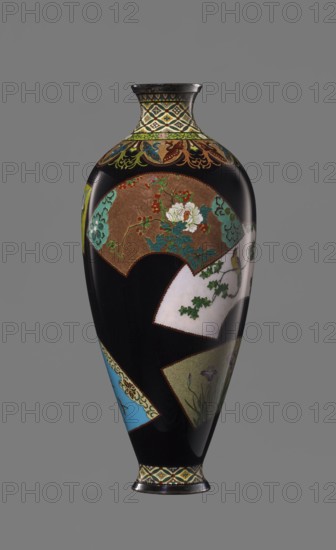 Vase by Namikawa Yasuyuki 1845–1927, cloisonné enamel, ca. 1890–1905 Meiji period. Small, slender vase tapering toward the bottom, terminating in a ring-shaped silver foot; short neck slightly parted at the spout enclosed by a silver ring. Ornamental shippo cloisonné border with rosettes in rhomboid fields at the foot and neck. Petal decoration with stylized phoenixes flowing down to the shoulders. Belly covered with glossy black enamel and six colorful fan-shaped reserves depicting various floral and bird motifs, executed in the yusen technique with silver wires. Silver plaque mounted in the mirror of the base engraved: Kyoto Namikawa. Kyoto, Japan. Height 18.0 cm; diameter 7.8 cm., A tall vase with a glossy black background decorated with a few fan-shaped panels showing floral and botanical scenes in colors including white, green, turquoise, brown, gold, red, blue, and purple, a band of ornate geometric and floral patterns in gold, green, turquoise, and cream around the neck and base...