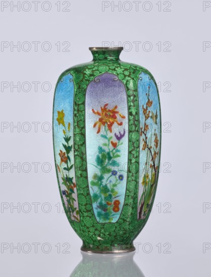 Vase, gift, repossession Krakow. Elongated hexagonal cloisonné enamel vase with a narrow spout. Decoration: small, densely spaced floral rosettes and butterflies on a black background; additional motifs include flowers, irises, and birds. Japanese, Meiji period 1868–1912, late 19th/early 20th century. Vessel. Height 12.5 cm; width 6.7 cm; depth 6.1 cm., A tall vase with a rounded body and narrow neck, predominantly green with a textured leafy pattern, featuring several elongated panels with pale blue to lavender backgrounds that display painted floral scenes in colors including orange, red, yellow, purple, blue, and green; the vase has metallic rims at the top and base and rests on a reflective surface, with the overall color palette showing green, blue, lavender, orange, yellow, red, purple, and metallic tones.