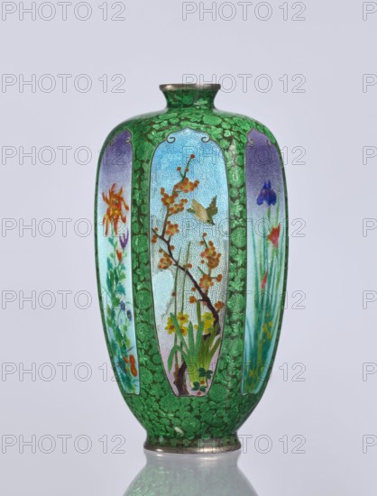 Vase, gift, repossession Krakow — elongated hexagonal vase with a narrow spout. Cloisonné enamel; decoration: small, densely spaced floral rosettes and butterflies on a black background, with flowers, irises, and birds motifs. Japanese, Meiji period 1868–1912, 19th/20th century. Vessel. Height 12.5 cm; width 6.7 cm; depth 6.1 cm., A decorative vase with a glossy green background patterned with darker green floral motifs and a metallic rim at the top and base; the vase has several vertical panels featuring painted botanical scenes with a light blue to pale background, showing branches with orange blossoms, green leaves and stems, yellow and red flowers, and a small beige bird in one panel, alongside panels containing purple and blue flowers and orange-red blooms; overall visible colors include various greens, light blue, purple, blue, orange, yellow, red, beige, and metallic silver.