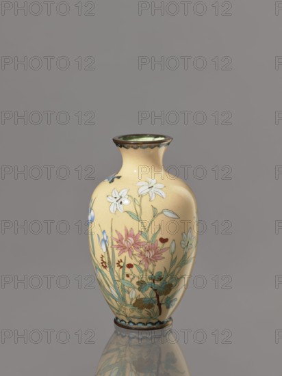 Vase, ; decorated with flowers and birds; cloisonné enamel; Meiji period, ca. 1900; Japan; vessel; height 12.2 cm, diameter 7.1 cm., A small vase with a rounded body and narrow neck sits against a gray background, its surface a warm yellow with a glossy finish, decorated with a painted floral scene featuring white, pink, blue, red, and green tones; the rim and foot have darker brown edging, and the vase casts a faint reflection below.