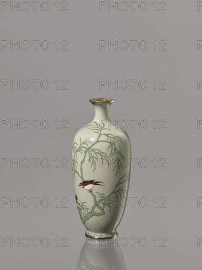 Vase, Cloisonné enamel vase with a short, thin, flared neck. Decoration of plants and swallows on a gray-green background. Japanese, Meiji period 1868–1912, late 19th/early 20th century. Vessel; height 12.1 cm, diameter 5.3 cm., A pale celadon vase with a narrow neck and slightly flared rim stands against a neutral gray background, decorated with a painted scene of a willow-like tree with slender green leaves and twisting branches, and a small bird with dark brown and cream plumage perched on a branch; the rim and base show a metallic gold tone, and the vase casts a subtle reflection on the surface beneath it.