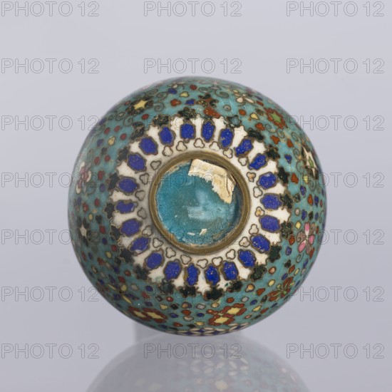Vase, cloisonné enamel. Vase with a spherical belly and a long cylindrical neck decorated on the entire surface with small floral and geometric motifs on a turquoise background. Japanese, Nagoya; Meiji period, ca. 1880. Vessel; height 9 cm, diameter 5.7 cm., A rounded decorative object with a dominant turquoise background covered in a dense pattern of small floral and geometric motifs in colors including blue, white, red, green, pink, yellow, black, and gold, featuring a central circular depression rimmed in gold with a worn turquoise interior and surrounded by a ring of alternating white and deep blue petal-like shapes, all shown against a pale gray background with a faint reflection of the object beneath it.