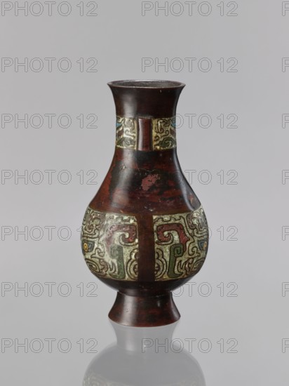 Vase, Chinese, taotie iconography, Qing dynasty 1644–1911, 19th century, ceremonial/ritual vessel, vessel, height 24 cm, diameter 13.1 cm, A single vase with a narrow flaring neck, a bulbous midsection, and a flared foot is shown against a plain gray background; the vase has a dark brown surface with areas of worn reddish-brown, and bands of ornate decorative panels around the neck and widest part that display swirling abstract patterns in muted green, pale yellow, faded red, blue, and touches of black; the finish appears slightly aged with small spots of abrasion, and the vase casts a soft reflection on the surface beneath it.