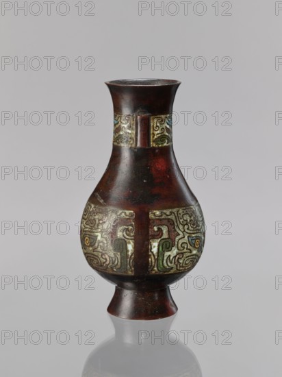 Vase, Chinese, taotie motif, Qing dynasty 1644–1911, 19th century, ceremonial/ritual vessel, porcelain/ceramic vessel, height 24 cm, diameter 13.1 cm, China place of origin uncertain, A single vase with a flared rim and a narrow neck widening into a bulbous body above a flared foot, shown against a plain light gray background; the vase surface is primarily dark brown with reddish undertones and a glossy patina, and it bears a band of ornate raised decoration around the midsection and another narrower band near the neck featuring swirling abstract motifs in muted green, pale yellow, light blue, and olive hues set against a lighter, aged background; the upper rim and lower foot remain the dark brown color, and the vase casts a soft reflection on the surface below.