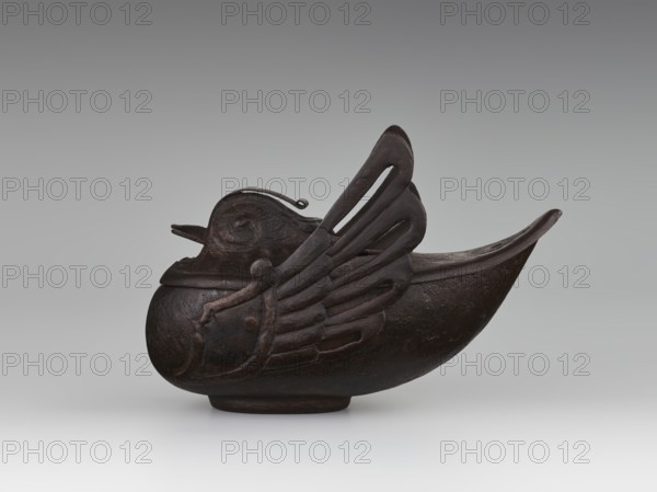 Duck incense burner, Chinese, Qing dynasty 1644–1911, 19th century, porcelain vessel shaped as ducks with wings, incense burner, height 9.7 cm, width 13.6 cm., A dark brown sculpted vessel shaped like a stylized bird with a rounded body and an elongated upturned tail, showing carved wing forms with openwork slits and layered feather details, a molded head with a short beak and a small loop on top, and a low circular base, placed against a smooth pale gray background with a subtle gradient.