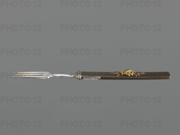 Fork with knife handle kozuka, Japanese, Edo period 1603–1868, 18th century. Melee weapon accessory for swords katana — kozuka. Plastic decoration: chrysanthemum flower with two leaves; textured background. Materials: plastic. Function: cutlery. Dimensions: height 16.6 cm, width 1.4 cm, depth 0.8 cm., A long metal fork with a silver-toned pronged end and a dark brown handle is shown against a solid gray background; the handle features a raised decorative element in gold and copper tones and a silver-toned ferrule where the metal meets the handle.