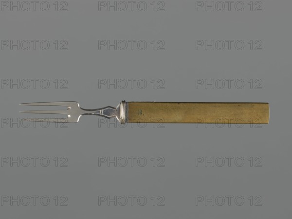 Fork with knife handle kozuka, Japanese, Edo period 1603–1868, 18th century. Kozuka for katana; metal handle with applied plastic decoration depicting grazing horses and a snake. Materials: metal; function: cutlery/knife handle for sword. Dimensions: height 17 cm, width 0.9 cm, depth 0.6 cm. Categories/subjects: snakes, horses, animals, handles, forks, swords, weapons., A metal fork with a silver-toned three-pronged head and a narrow neck connects to a rectangular handle with a brass or gold-toned finish; the background is a uniform gray.