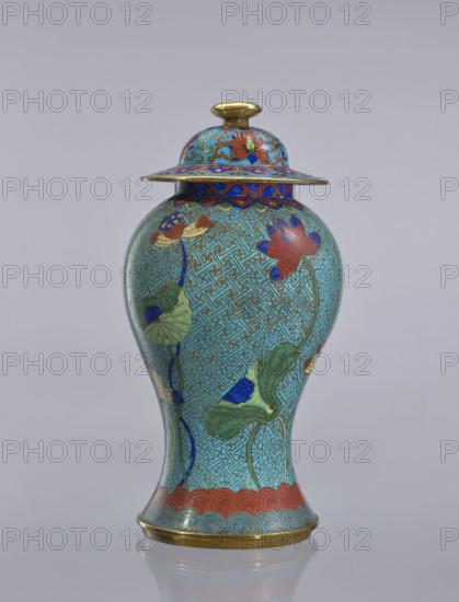 Vase with cover, Chinese, Qing dynasty 1644–1911, cloisonné enamel with lotus and geometric decorations, decorative vessel, 18th century, China; height 37 cm., A lidded vase with a bulbous body and a flared base and rim, decorated in a predominately turquoise-blue ground with an intricate repeated geometric pattern, featuring stylized lotus flowers and large green leaves with stems in darker blue, lotus blossoms in red and accents of deep blue and pale yellow, a band of red scalloped decoration near the base and a narrow gold-colored metal rim at the bottom, the lid topped with a small gold-colored knob and showing additional decorative motifs in red, blue, green, and gold on its domed surface and wide overhanging rim, all set against a light gray background.