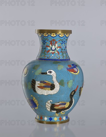 Vase, Gift; Paderewski, Ignacy Jan 1860–1941. Chinese art; Qing 1644–1911. Cloisonné enamel decorative vessel on a foot with a neck. Decoration: ducks on a turquoise background; lotus tendril ornament on the neck. 19th century, China. Height 23.5 cm., A rounded vase with a flared neck, predominantly turquoise blue, decorated with a repeating pattern of flowing concentric lines and a group of stylized ducks in white, black, gold, red, blue, and yellow; the neck features ornate floral motifs in red, white, blue, green, and gold with a gold rim at the top, and the base has a narrow band of geometric diamond shapes in blue, red, gold, white, and yellow above a gold foot.