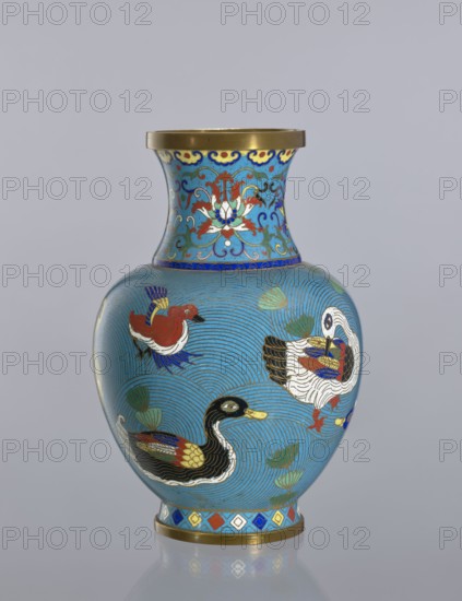 Vase, Cloisonné enamel decorative vessel vase on a foot, with a neck. Decoration: ducks on a turquoise background; lotus tendril on the neck. Chinese; Qing dynasty 1644–1911, 19th century. Height: 23.5 cm; material: cloisonné enamel., A rounded vase with a flared neck, shown against a plain light gray background, decorated with a bright turquoise-blue ground and detailed enamel designs in colors including gold, red, white, black, dark blue, green, and yellow; the neck features a floral motif in red, white, dark blue, and gold with scrolling accents, and a gold rim at the top; the bulbous body shows a group of stylized birds in varied poses, rendered in combinations of black, white, red, gold, blue, and green, set against a background of concentric wave-like lines and scattered aquatic plant shapes in green; the foot of the vase has a band of geometric lozenges in red, blue, yellow, white, and gold and a gold base rim.