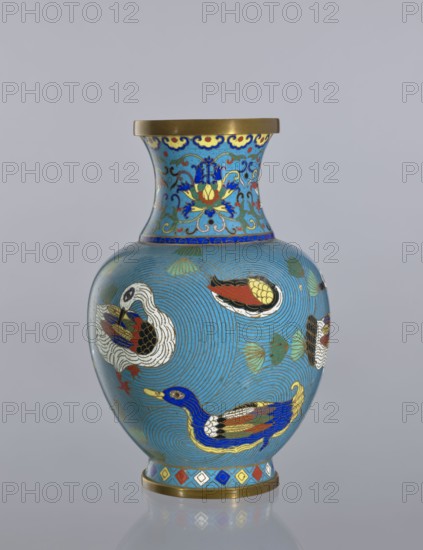 Vase, Cloisonné enamel decorative vessel from China, Qing dynasty 1644–1911, 19th century. Vase on a foot with a neck, height 23.5 cm. Decoration: ducks on a turquoise background and lotus tendril ornament., A rounded vase with a flared neck sits against a plain gray background; the vase is predominantly light blue with concentric swirl patterns and decorated with a few stylized birds rendered in bright colors including blue, yellow, red, white, black, and gold; the neck features ornate floral and scroll motifs in blue, yellow, red, and gold on a lighter blue ground, with a gold rim at the top; the body shows additional small leaf-like shapes in green and gold, and a band of geometric diamond shapes in blue, red, yellow, white, and gold encircles the base above a gold foot.