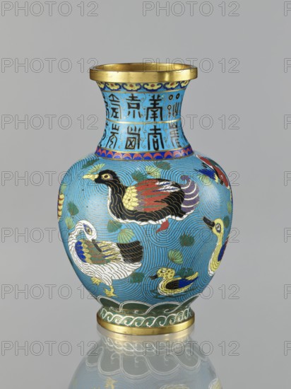 Vase, gift, Chinese, Qing 1644–1911, cloisonné enamel, depicts ducks on a turquoise background with an archaizing inscription on the neck, longevity shou iconography, vase on a foot with a neck, 19th century, China, vessel, height 23.3 cm, A blue vase with a gold rim and gold base featuring a pattern of several ducks in various colors including black, white, red, yellow, green, blue, and purple, with stylized wave and leaf motifs in shades of green and turquoise; the neck of the vase shows a band with decorative motifs in blue, turquoise, and gold; the vase sits on a reflective surface that mirrors the base and lower decoration, and the background is a plain light gray.