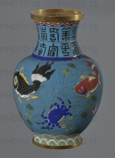 Vase, 19th century, China. Cloisonné enamel vessel on a foot with a neck, height 23.5 cm, diameter 9.3 cm. Decoration: fish and crabs on a turquoise background; archaizing inscription on the neck. Qing dynasty style; Chinese., A rounded vase with a flared neck and gold rim sits against a neutral gray background, the surface covered in a bright turquoise-blue ground with swirling wave patterns in darker blue lines. The main decoration shows a few stylized aquatic creatures including a black and gold fish with white and yellow fins, a red and white fish with yellow fins and a smiling face, and a vivid cobalt-blue crab with yellow details. Small green leaf-like motifs float among the waves. The neck area is decorated with vertical dark motifs on the same blue background and a narrow band of deep blue with a repeating geometric edge. The foot of the vase has a pale green band with interlocking wave-like scrolls and a gold base rim. Colors visible include turquoise-blue, deep blue, cobalt b...