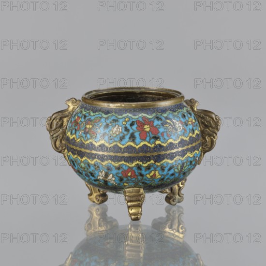 Ding incense burner, cloisonné enamel, 18th century China. Tripod vessel with two plastically shaped handles, no cover. Floral decoration in striped arrangements with butterflies, peonies, and fantasy beasts; Qing style; ceremonial vessel. Height 8.4 cm, width 12.4 cm, diameter 9.8 cm., A small rounded metal vessel with a wide open top, supported by three short ornate legs and featuring a pair of decorative handles on opposite sides; the body is covered in a patterned enamel in shades of turquoise blue, dark blue, yellow, red, green, white, and black with floral and wave-like motifs, and the metal rim, legs, and handles show a golden-bronze color.