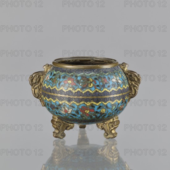 Ding incense burner, Chinese cloisonné ceremonial vessel, Qing dynasty 18th century. Ding tripod incense burner with two plastically shaped handles; no cover. Floral decoration in striped arrangements with butterflies, peonies, and fantastical beasts. Height 8.4 cm; width 12.4 cm; diameter 9.8 cm., A small rounded metal vessel with ornate handles and feet sits against a plain gray background, decorated in a mottled pattern of bright turquoise and blue with accents of yellow, red, white, green, and dark blue; the metal rims, handles, and tripod feet are a brass or gold tone, and a soft reflection of the vessel appears on the surface below.