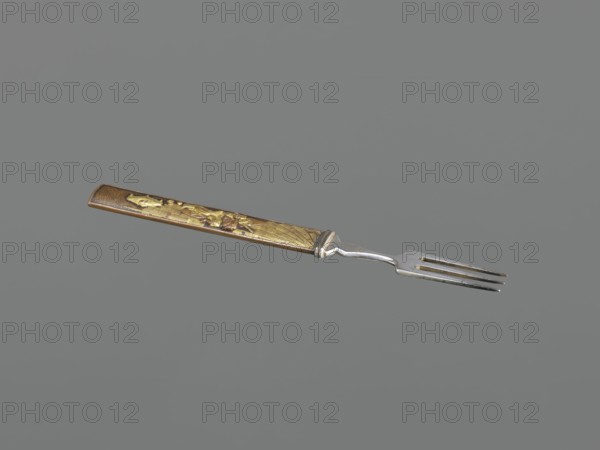 Fork with knife handle kozuka, Japanese, Edo period 1603–1868, 18th century, kozuka for katana, fork, melee weapon/weapon accessory, materials: metal cutlery, height 16.9 cm, width 1.4 cm., A fork with a metallic silver pronged head and a decorative handle in shades of gold and brown is shown against a plain gray background; the handle has raised textured and patterned areas and a tapered rectangular shape, and the metal section connecting handle to prongs has a slightly curved profile.