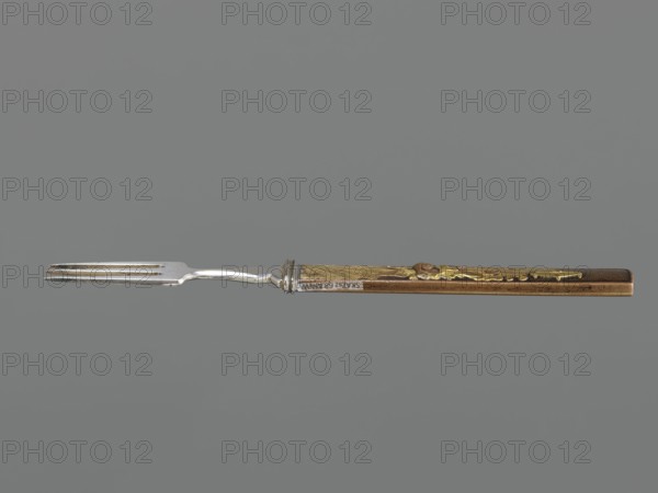 Fork with knife handle kozuka, Japanese, Edo period 1603–1868, 18th century; material: metal; function: kozuka small knife handle used with swords/katana; subject: fork/knife handle design; dimensions: height 16.9 cm, width 1.4 cm; related to Japanese cutlery and melee weapon fittings., A single fork laid horizontally against a neutral gray background, showing a metal pronged end that is silver in color and a long handle that is brown with gold decorative accents; the handle has textured and raised ornamental details and the metal near the handle joins shows a small ridged collar.