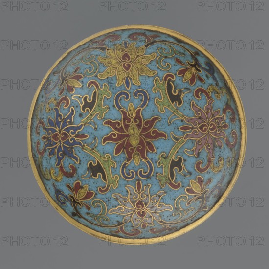 Box with a lid. Cylindrical spheroidal box on a separate ring foot with a slightly convex lid, decorated overall with multi-coloured lotus tendrils on a turquoise ground. Foot bears a band with curling silkworm-larvae motif. Rounded edge of lid, storage section, lower edge of foot, interior and bottom are gilded. Bottom engraved with the inscription made in the Qianlong era and a workshop/guild mark yue. Pair with a similar box slightly different shape, height, and ornamentation. Cloisonné enamel. Qing dynasty, Qianlong period 18th century, China. Height 4 cm; diameter 6.7 cm., A round decorative bowl with a turquoise blue interior featuring a repeating floral and scroll pattern in a few colors including gold, red, dark blue, green, black, and purple, outlined in thin gold lines; the rim is gold and the background outside the bowl is gray.