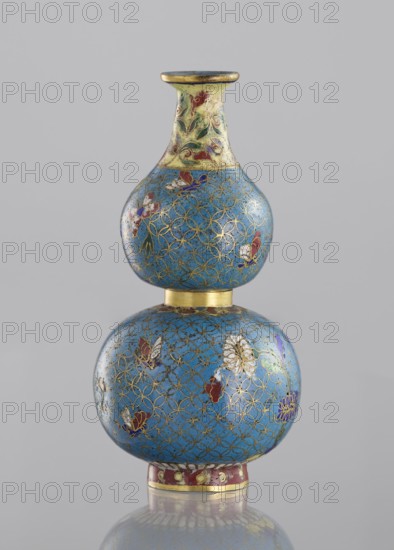 Double gourd-shaped vase;, Cloisonné enamel decorative vessel, Qing dynasty 1644–1911, 19th century, China. Decoration: flowers and butterflies/insects on a turquoise ground with a grid of circles; yellow neck. Vase twisted from two parts. Height 14 cm; diameter 7 cm., A double-gourd shaped object with a glossy blue surface decorated with a repeating gold lattice pattern and floral motifs in red, white, purple, green, and gold, a narrow yellow and green neck with painted leaf-like designs, a gold-colored band separating the two rounded sections, and a red and gold base, all shown against a plain light gray background.