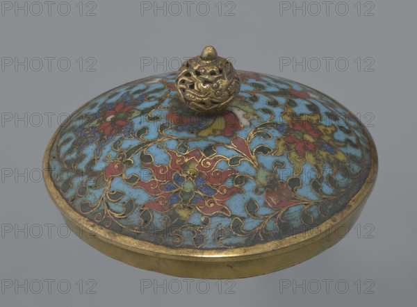 Tin with a lid, Chinese art, Chinese, Qing 1644–1911, Qianlong period, cloisonné enamel; cylindrical tin with a wide plate-like collar extending beyond the vessel walls and slightly rising at the rim. Domed lid with a handle shaped as a decorative openwork knob: a dragon in clouds facing a pearl atop the handle. Exterior of vessel box and collar decorated with multicolored red, blue, green, yellow, white small-flower ornament — branches with rosettes, buds, and leaves — on a turquoise background. Lid decorated with a lotus tendril of four geometrically arranged flowers and surrounding branches; central multi-petal rosette beneath the metal handle, also on a turquoise ground. Bottom filled with a rich multicolored composition of elements reminiscent of Buddhist symbols — a vajra and Dharma wheel forming the inner central rosette, with two-colored red and blue ribbons between the symbols. Interior of box and lid lack enamel decoration; all interior elements are gilded. Possibly used in r...