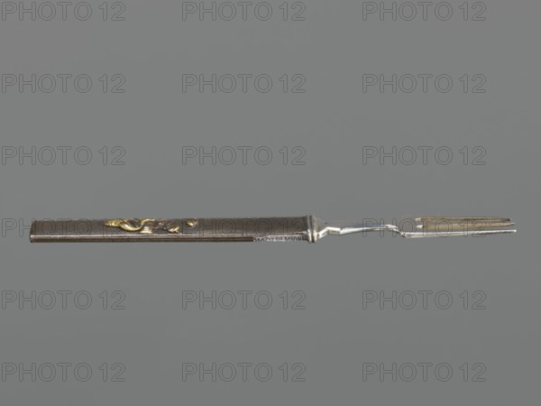 Fork with knife handle kozuka, Japanese, Edo period 1603–1868, 18th century, katana kozuka, melee weapon accessory, forks, cutlery; materials implied knife handle/kozuka; dimensions: height 16.9 cm, width 1.4 cm., A slender metal fork with a straight handle and a slightly curved neck is shown against a plain gray background; the handle appears dark brown with a textured surface and has a few small gold-colored decorative elements, while the fork head and neck are silver with areas of tarnish and wear.