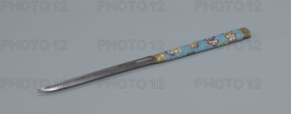 Travel cutlery set in case; Chinese, Qing dynasty 1644–1911, 19th century. Includes: a Knife with a cloisonné enamel handle and steel blade; b–c Ivory chopsticks decorated with an inlaid black lacquer ornament at the top in the form of a border; d File decorated similarly to the chopsticks; e Cloisonné enamel case reaching 3/4 the height of the cutlery, with bronze fittings engraved with ornamentation at top and bottom, interior lined with wood. Chopsticks and file are held by a band decorated with a matching border; a narrow cotton-silk strap with fringes is attached. Case decorated with flowers in two reserves and plant tendrils in the background. Motifs include plant designs and a swastika. Function: travel cutlery. Length: 28 cm case., A long metal blade with a pointed tip lies diagonally on a gray background, attached to a cylindrical handle decorated in light blue with floral patterns in red, white, yellow, and dark blue, and accented with metallic gold-colored bands at the blade...
