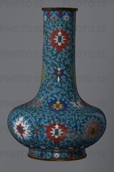 Vase, gift, Chinese, Qing dynasty 1644–1911, cloisonné enamel with lotus and lotus tendril ornament. Vase with a long, wide neck, supported on a separate ring-shaped foot, with a flattened spherical belly, the main decoration a dense, multicolored lotus tendril surrounding the entire surface. Foot decorated with an ornamental band of small flowers and leaves. Upper edge of the neck at the rim decorated with a border of ruyi-heads. Neck ends with a thick, ungilded metal ring. 2nd half of the 18th century, China. Vessel; height 37.8 cm, diameter 15.5 cm., A tall, bulbous vase with a long narrow neck sits against a gray background, covered in an intricate floral pattern on a turquoise-blue field; the design features large stylized flowers in red, white, yellow, blue, purple, and green, surrounded by curling dark green vine-like motifs and small decorative floral borders, with a dark brown rim at the top and a slightly flared base rim showing additional small flower motifs.