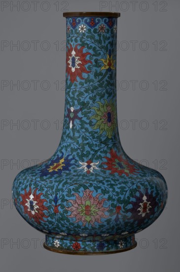 Vase, cloisonné enamel; Chinese, Qing dynasty 2nd half of the 18th century. Vessel with a long, wide neck, supported on a separate ring-shaped foot, with a flattened spherical belly. Main decoration: dense, multi-colored lotus tendril surrounding the entire surface. Foot decorated with an ornamental band of small flowers and leaves. Upper edge of the neck, at the rim, has a border formed of ruyi-heads. Neck ends with a thick, ungilded metal ring. Height 37.8 cm; diameter 15.5 cm., A tall rounded vase with a narrow neck and wide bulbous base, covered all over in an intricate floral and foliate pattern in vivid colors against a turquoise blue background; the decoration includes a group of stylized flowers and swirling leaves in red, green, yellow, white, purple, navy blue, and pink, with fine dark outlines and small ornamental motifs around the rim and foot; the rim and the foot edges appear to be metallic brown, and the overall surface has a smooth, glossy finish.