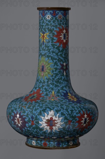 Vase, cloisonné enamel, Qing dynasty 2nd half of the 18th century, China. Vase with a long, wide neck supported on a separate ring-shaped foot, with a flattened spherical belly. Main decoration: dense, multi-colored lotus tendril surrounding the entire surface. Foot decorated with an ornamental band of small flowers and leaves. Upper edge of the neck at the rim decorated with a border of ruyi auspicious scepter heads. Neck ends with a thick, ungilded metal ring. Height 37.8 cm; diameter 15.5 cm., A tall, bulbous vase with a narrow neck and flared mouth, decorated all over in a blue background with swirling green vine-like patterns and a repeating motif of stylized floral or sunburst shapes in colors including red, white, yellow, green, purple, and dark blue, with a band of small flower motifs around the base and a thin darker rim at the mouth and foot.