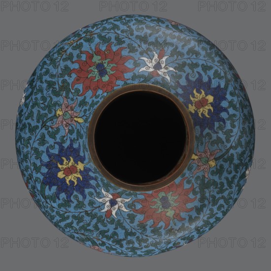 Vase, Chinese, Qing dynasty 1644–1911, 2nd half of the 18th century. Cloisonné enamel vessel with a long, wide neck supported on a separate ring-shaped foot and a flattened spherical belly. Main decoration: dense, multicolored lotus tendril surrounding the entire surface; foot decorated with an ornamental band of small flowers and leaves; upper edge of the neck at the rim bordered with ruyi-heads. Neck ends with a thick, ungilded metal ring. Height 37.8 cm; diameter 15.5 cm., A rounded vessel viewed from above with a dark central opening surrounded by a narrow brown rim, the body covered in an intricate floral pattern on a blue background; a group of stylized flowers in red, white, yellow, and dark blue are scattered among green vine-like shapes and teal foliage, with accents of dark green and touches of lighter blue throughout.