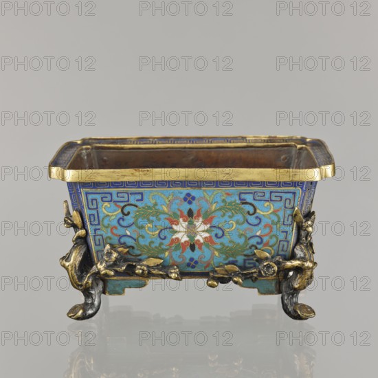 Flower pot;, Chinese, Qing dynasty 1644–1911. Cloisonné enamel incense burner on four legs; decoration of lotuses and lotus tendrils on a turquoise background, legs in the shape of flowered trunks plum branches in gilded bronze; ornament motifs include plum trees, cracked ice, and meander. 18th century. Vessel jardiniere/incense burner. Height 9.5 cm; width 17.2 cm; depth 12.0 cm., A rectangular decorative container with a gold rim sits on a reflective surface, showing a front panel decorated in bright blue and turquoise enamel with a complex floral and scroll pattern in green, red, white, and dark blue; the panel is bordered by a geometric band in blue and gold. The container rests on ornate gilt and dark metal feet shaped like stylized branches and leaves with small floral details, and the interior appears coppery brown. The visible colors include gold, blue, turquoise, green, red, white, dark blue, coppery brown, and dark metallic tones.