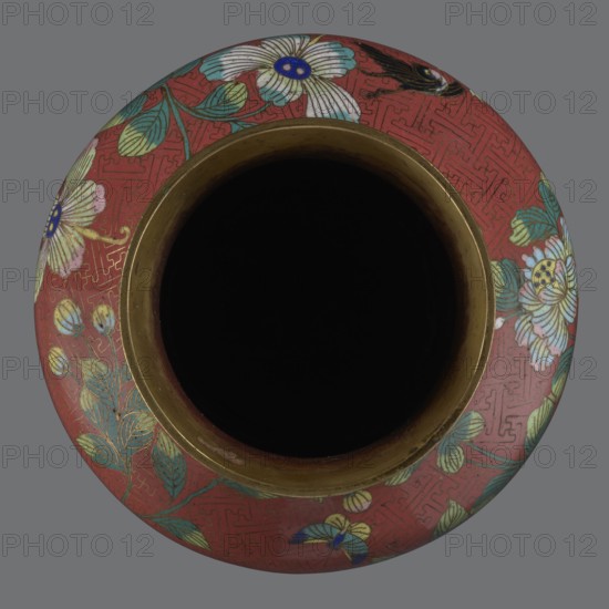 Vase, Paderewski, Ignacy Jan 1860–1941. Chinese art; Qing dynasty 1644–1911, Xianfeng period 1851–1861; cloisonné enamel. Flowers, floral pattern, meander ornament. The vase is set on a tall, conical foot flaring downwards, terminating in a metal ring, decorated with a lotus tendril. The neck is short and wide, also topped with a metal ring, below which is a border composed of ruyi heads. The belly and neck are decorated with a continuous composition of flowers and plum branches placed against a red Chinese meander background. 1st half of the 19th century. China. Vessel; height 25.1 cm, diameter 16.5 cm, weight 1.5 kg., A top-down view of a round vessel with a wide dark interior and a metallic inner rim; the exterior surface is predominantly red with floral and leaf patterns in shades of white, blue, green, yellow, and pink, and a few small butterfly or petal-like shapes, all set against a gray background.