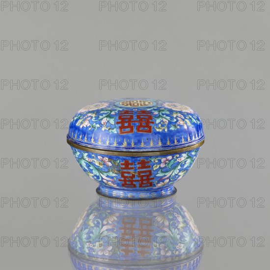 Incense burner - bowl with a lid, Chinese, Qing dynasty 1644–1911, 18th/19th century. Painted enamel decoration on a navy blue background with flower tendrils peony, bats, flowers, coins, and the character shuangxi double happiness, usually used in China in the context of marriage. Ceremonial vessel — censer/incense burner. Height 6.4 cm; diameter 9.7 cm; weight 0.17 kg., A small round lidded box sits centered against a plain light gray background, showing a glossy surface and a clear reflection beneath it. The box is predominantly bright blue with decorative floral patterns in shades of green, pink, white, and pale purple, and has ornate gold accents along the rim and base. There are bold rectangular motifs in deep red on both the lid and the body, and the overall finish appears enamel-like and polished.