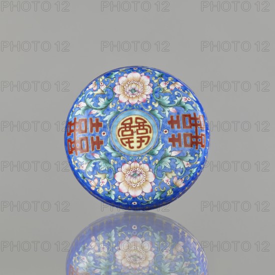 Incense burner - bowl with a lid; maker, ; Chinese; Qing dynasty 1644–1911; 18th/19th century; painted enamel on navy blue background; decorated with bats, plant tendril peony, flowers, coins, and the character shuangxi double happiness, usually used in China in the context of marriage; ceremonial vessel / censer; height 6.4 cm, diameter 9.7 cm, weight 0.17 kg., A round decorative object with a glossy blue background featuring a symmetrical floral design in pink, green, and white, with swirling green leaves and tendrils, and circular central medallion in yellow and red; the piece rests against a neutral gray background and casts a soft reflective mirror image below that echoes the colors of blue, pink, green, yellow, and red.