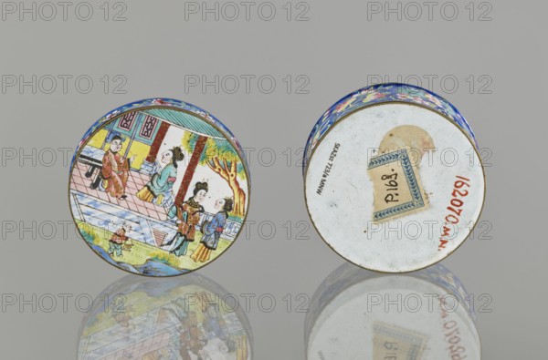 Box with a lid;, Painted enamel box depicting figurative scenes with peonies, grapes, and peaches. Materials: painted enamel. Cultures: Chinese Qing dynasty, 1644–1911 and Vietnamese Nguyen dynasty, 1802–1945; 19th century. Function: container. Dimensions: height 3.3 cm, diameter 6.3 cm., A pair of small round objects sit on a reflective surface against a neutral gray background, one showing a colorful painted scene with figures in traditional clothing near architectural elements and a tree, the other showing a mostly white underside with a small decorative paper fragment and some discoloration; visible colors include blue, yellow, red, green, pink, brown, white, and black.