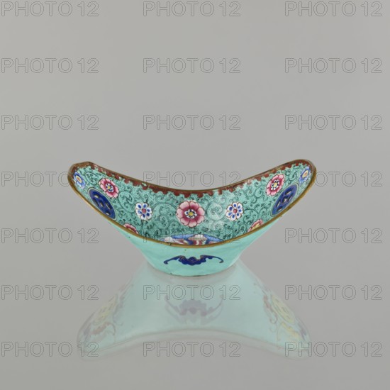 Bowl, painted enamel, Qing 1644–1911, 18th/19th century, China; decorated with boats, bats iconography, lotuses, coins, and floral tendril motifs symbolizing happiness; vessel; height 6.3 cm, width 8.5 cm, depth 15.3 cm;, A small decorative bowl with a curved, crescent-like shape sits on a reflective surface, showing a mirrored image beneath; the exterior and interior surfaces feature a dominant turquoise color with intricate swirling patterns in darker green, accented by pink and white floral motifs and deep blue rounded medallions, while the rim is outlined in a metallic gold tone and there are touches of red along the inner edge.
