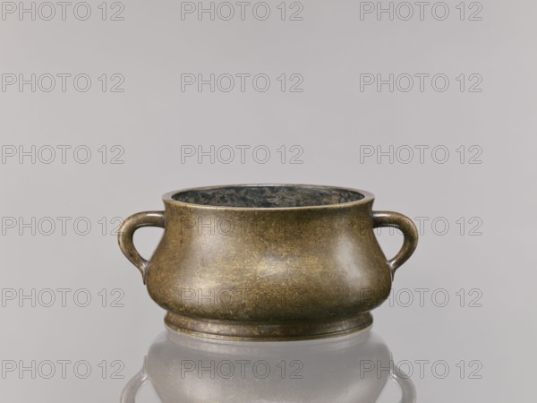 Censer, Chinese, Qing dynasty 1644–1911, 18th century. Ceremonial/ritual vessel; backdated signatures. Material not specified. Height 8.5 cm; diameter 16.8 cm., A low, rounded metal vessel with a pair of looped handles sits centered on a reflective surface; the vessel has a mottled bronze and brown exterior with subtle greenish and dark patina inside and along the rim, and the background is a smooth pale gray.