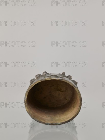 Bell linzhong, Paderewski, Ignacy Jan 1860–1941, Chinese, Qing dynasty Daoguang, 1821–1850, 1825, bronze musical instrument idiophone percussion, used in music and religious rites, decorated with ideograms and meander ornament, height 29.0 cm, width 20.0 cm, depth 17.0 cm., A cylindrical hollow object lying on its side with a rounded open mouth showing an interior surface in shades of brown and muted green, an outer rim with tarnished metallic tones of gold and dark gray, decorative raised elements around the upper exterior in dull gray and brown, and a pale neutral background in light gray.
