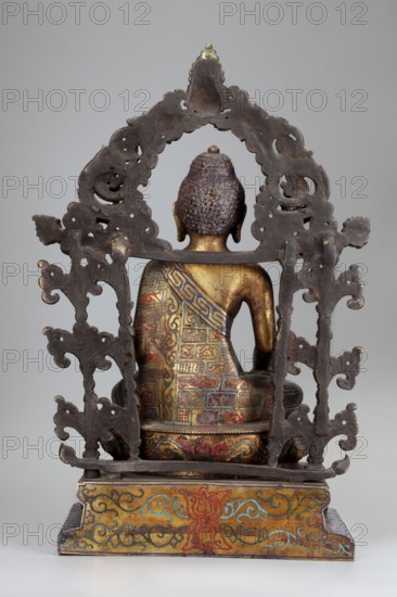 Shakyamuni Buddha, gift, Chinese, Himalayan/Tibetan Buddhist art, Sino-Tibetan style, Buddha iconography with bowls, lotus throne, ushnisha, vajras; 18th century, China; sculpture; height 38.0 cm, width 25.0 cm, depth 13.7 cm., A seated metal figure viewed from the back with a textured purple head and a golden neck and shoulders, wearing a colorful patterned garment in shades of blue, red, green, and gold; the figure sits on a decorated base with gold, red, blue, and green motifs, and is framed by an ornate dark metal arch with intricate cutouts and scroll-like shapes against a neutral gray background.