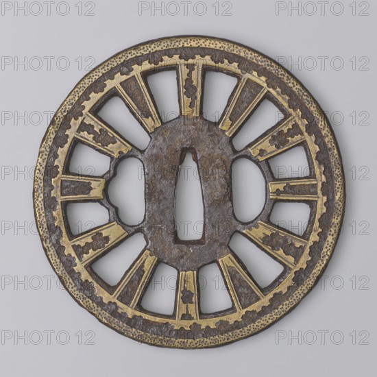 Crossguard tsuba, Shôami, / school and Migaki, attribution uncertain; unsigned. Katana crossguard tsuba of the kuruma tsuba type, of the Buddhist Law Circle; oval seppa dai. Both sides decorated with irregular brass inlaid spots; edge with two stripes, the outer stripe filled with fine dots. 18th century Edo period, 1603–1868, Japan. Tsuba; diameter 8.5 cm, thickness 0.5 cm., A circular metal object with a central elongated opening and two smaller rounded openings on either side, featuring a radial openwork design of spokes and segmented panels; the surface shows a combination of dark brown rusted metal and bright golden inlaid highlights, with textured dotted and scalloped decorative borders around the rim; overall the object appears flat and ornamental with alternating solid and open sections forming a symmetrical pattern.