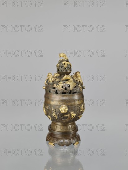 Censer with a cover on a base;, Qing dynasty 18th century, China. Bronze vessel censer with a high foot, openwork cover and handles; cover has removable knob. Decoration: dragons and hôô phoenix birds on the cover; various animals tigers, birds, fish, phoenixes, dragon with a pearl, clouds, sea waves, geometric patterns and meander ornament on the body and handles. Ritual/ceremonial vessel. Height 22.0 cm; width 21.0 cm; depth 17.7 cm., A decorative metal vessel with a rounded body and a domed, openwork lid sits on a carved round base; the object shows a combination of dark bronze and bright gold tones, with gilded ornamental figures and motifs attached to the lid and body, including small animal-like forms and cloud-shaped cutouts, and a finial topped by a sculpted figure; the base has fluted and banded detailing and echoes the dark bronze and gold coloration, and the whole piece casts a faint reflection on a smooth, neutral gray surface against a plain pale gray background.