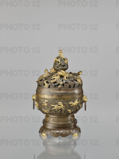 Censer with a cover on a base;, Qing 1644–1911, Chinese art. Ceremonial/ritual vessel: censer with a high foot, openwork cover and handles. Decoration: dragons and hôô phoenix birds on the cover; various animals tigers, birds, fish, phoenixes on the body; dragon with a pearl, clouds, sea waves, geometric patterns, meander ornament. Cover with removable knob. 18th century, China. Dimensions: height 22.0 cm, width 21.0 cm, depth 17.7 cm., A decorative metal vessel with a lid sits against a plain light gray background, showing a combination of dark bronze and bright gold tones; the lid has openwork with a few sculpted figures on top and a gold finial, the body of the vessel is rounded with raised sculptural motifs in gold and dark bronze, a few ring handles hang from sculpted animal head mounts on the sides, the vessel rests on a tiered pedestal base that echoes the dark bronze and gold color palette and casts a soft reflection on the shiny surface beneath.