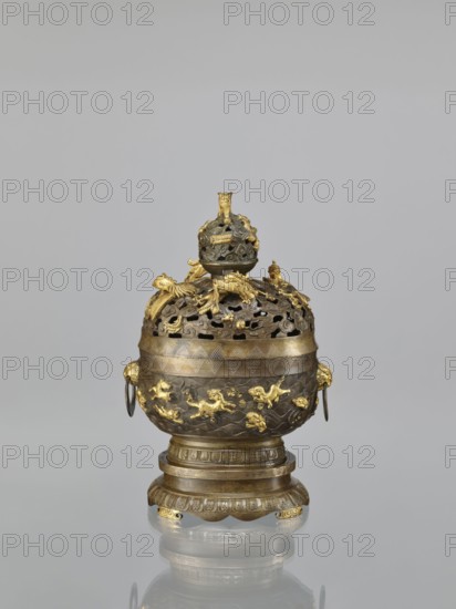 Censer with a cover on a base, Qing style, Chinese art; Chinese culture. Dragons iconography, handles, meander ornament, ceremonial/ritual vessel; tigers, sea waves, birds, dragon with a pearl, fish, clouds, phoenixes, geometric patterns. Censer with a high foot. Openwork cover and handles. Decoration: dragons and hôô birds on the cover; various animals on the belly. Cover with removable knob. 18th century, China. Vessel, censer. Height 22.0 cm, width 21.0 cm, depth 17.7 cm., An ornate metal vessel with a rounded body and domed, pierced lid sits on a tiered circular base; the vessel shows a mix of dark metallic and bright gold tones, with gold decorative figures and motifs in relief around the body and lid, gold ring handles at the sides, and sculpted gold elements atop the lid including a small finial; the base has carved bands and gold-accented scalloped feet, and the whole object is reflected faintly on a glossy surface beneath it against a pale gray background.